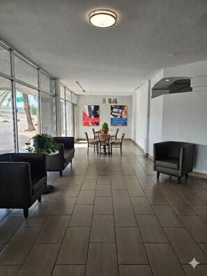 A hotel lobby with a reception desk, seating area, and large windows.
