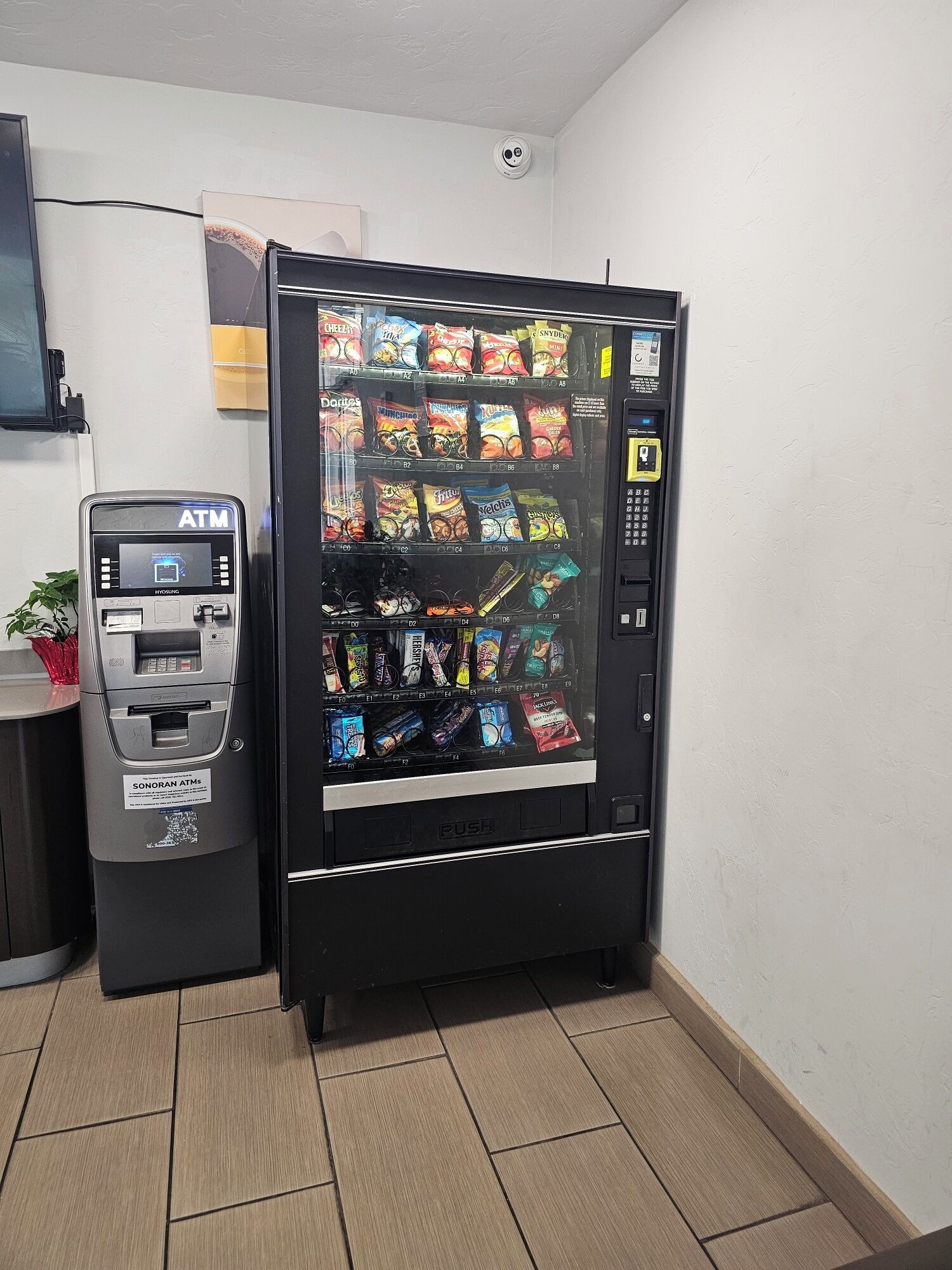 A vending machine with a variety of snacks and a payment terminal.