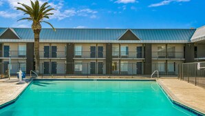 A hotel with a swimming pool, multiple balconies, and a palm tree. - Motel 6 Tucson, AZ (Tucson)