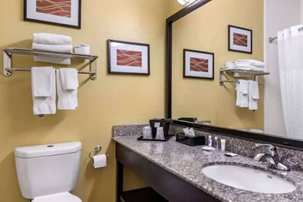 A bathroom with a white sink, a toilet, a towel rack, and framed pictures on the wall.