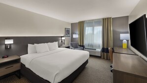 A hotel room with a large bed, a desk, a chair, a flat-screen TV, and a window with curtains. - Comfort Inn & Suites Austin North Loop (Austin)