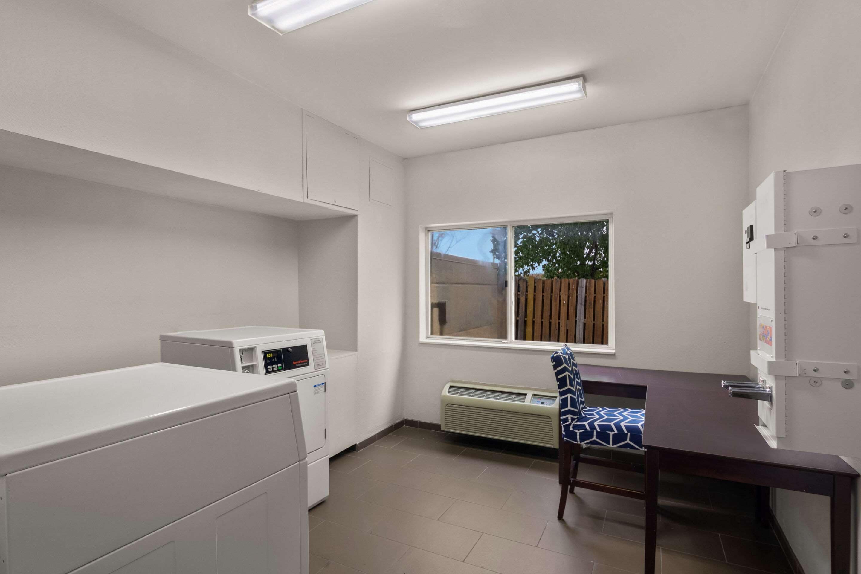 A laundry room with a washing machine, dryer, and ironing station.