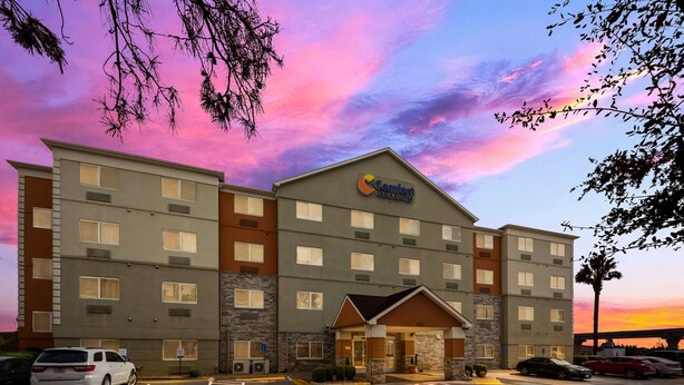 A multi-story hotel with a prominent sign, a parking lot, and a clear sky. - Comfort Inn & Suites Austin North Loop (Austin)