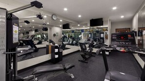 A gym with exercise equipment, mirrors, a clock, and a digital display. - Comfort Inn & Suites Austin North Loop (Austin)