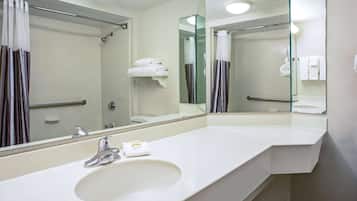 A modern bathroom with a large mirror, a sink, and a shower area.