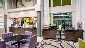 Un moderno vestíbulo de hotel con una barra de café, zona de estar y amplias ventanas.