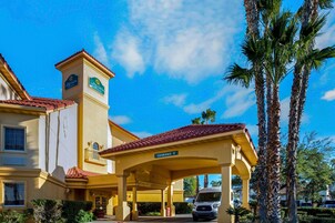 Un hotel con una torre destacada, un acceso cubierto y palmeras.