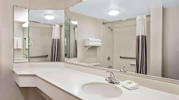 A modern bathroom with a large mirror, a white sink, and a shower area.