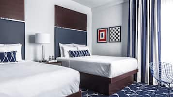 A hotel room with two beds, a desk, a chair, and a checkered wall decoration.