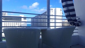 A balcony with two wicker chairs, a striped curtain, and a view of high-rise buildings and the ocean. - Albion South Beach Hotel (Miami Beach)