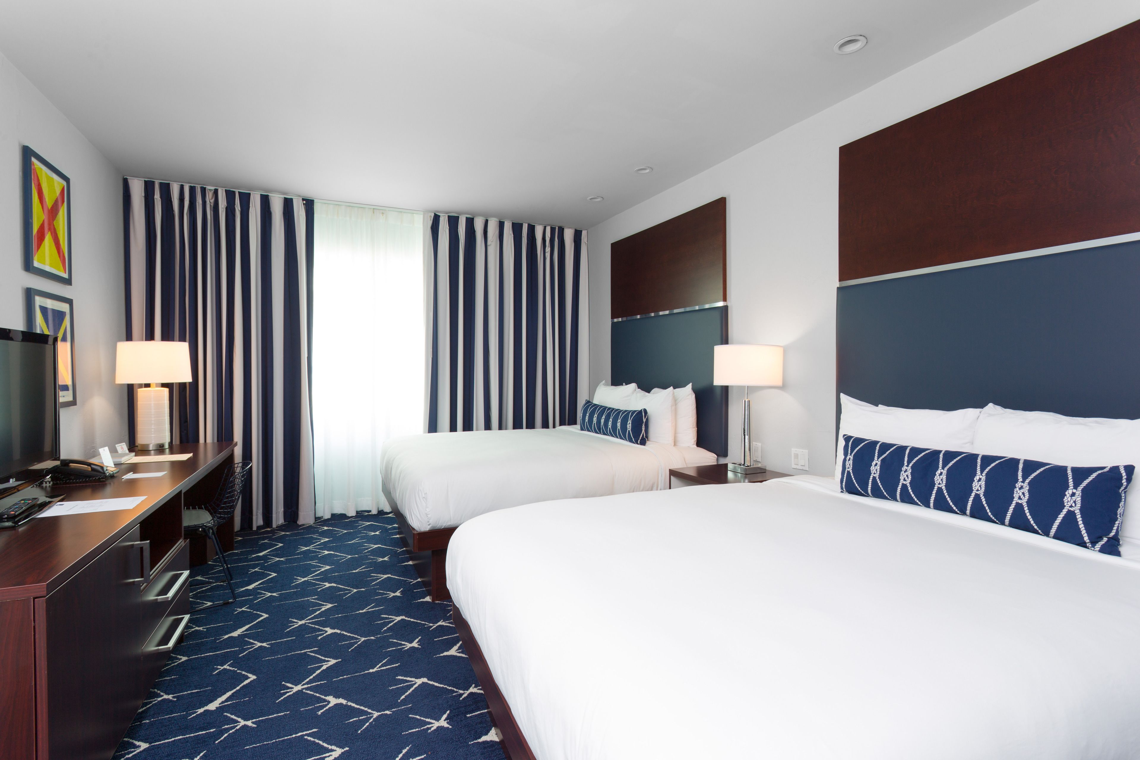 Een hotelkamer met twee bedden, een bureau en een stoel.