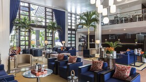 A spacious lobby with multiple seating areas, including sofas and armchairs, arranged around a central coffee table. There are large windows with curtains, allowing natural light to fill the space. - Albion South Beach Hotel (Miami Beach)