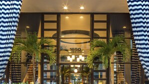 A hotel entrance with a glass facade, palm trees, and a sign reading "1650 James Ave." - Albion South Beach Hotel (Miami Beach)
