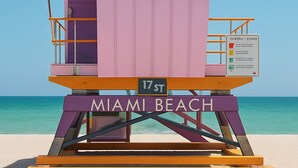 A lifeguard tower at Miami Beach with a flag, a sign indicating the address, and the name 'MIAMI BEACH' on the base. - Albion South Beach Hotel (Miami Beach)