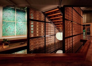 Un interior moderno con un separador de madera, una pared verde con objetos pequeños y una escalera.