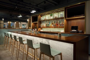 A hotel room with two beds, a desk, a TV, and a large window with a city view. at The Gates Hotel South Beach