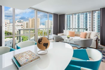 A modern reception area with a wooden reception desk, a large potted plant, and a seating area with chairs. at The Gates Hotel South Beach