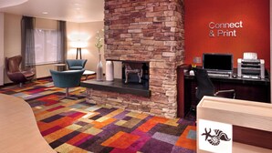 Un hall d’hôtel doté d’une cheminée en pierre, d’une moquette aux couleurs vives, d’un bureau avec un ordinateur et d’un panneau indiquant : « Connexion et impression ».