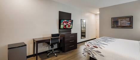 Une chambre d’hôtel équipée d’un lit, d’un bureau, d’une chaise, d’une télévision, d’une commode et d’un miroir.