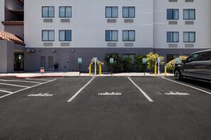A parking lot with electric vehicle charging stations, marked parking spaces, and a building with multiple windows and air conditioning units. - Red Roof Inn Tucson North - Marana (Tucson)