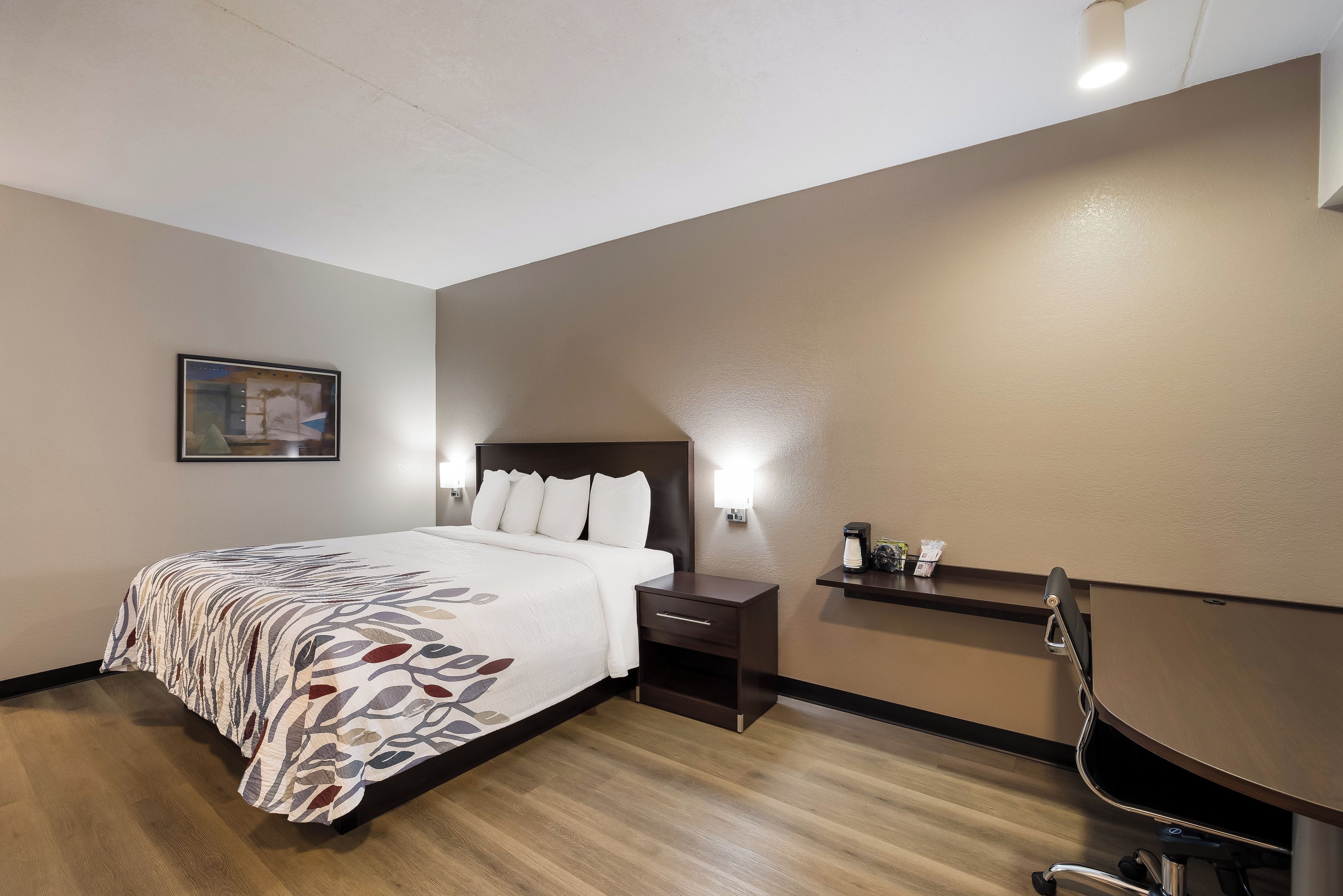 Una habitación de hotel con cama, mesita de noche, escritorio y silla.