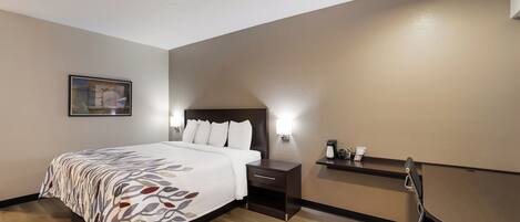 Una habitación de hotel con cama, mesita de noche, escritorio y silla.