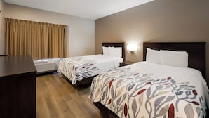 Ein Hotelzimmer mit zwei Betten, einem Schreibtisch und einem Fenster mit Vorhängen.