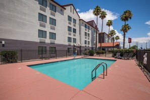 A hotel with a swimming pool, palm trees, and a clear blue sky. - Red Roof Inn Tucson North - Marana (Tucson)