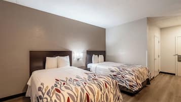 Una habitación de hotel con dos camas, piso de madera y una puerta blanca.