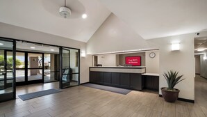 A reception area with a modern design, including a reception desk, a clock, and a potted plant. - Red Roof Inn Tucson North - Marana (Tucson)