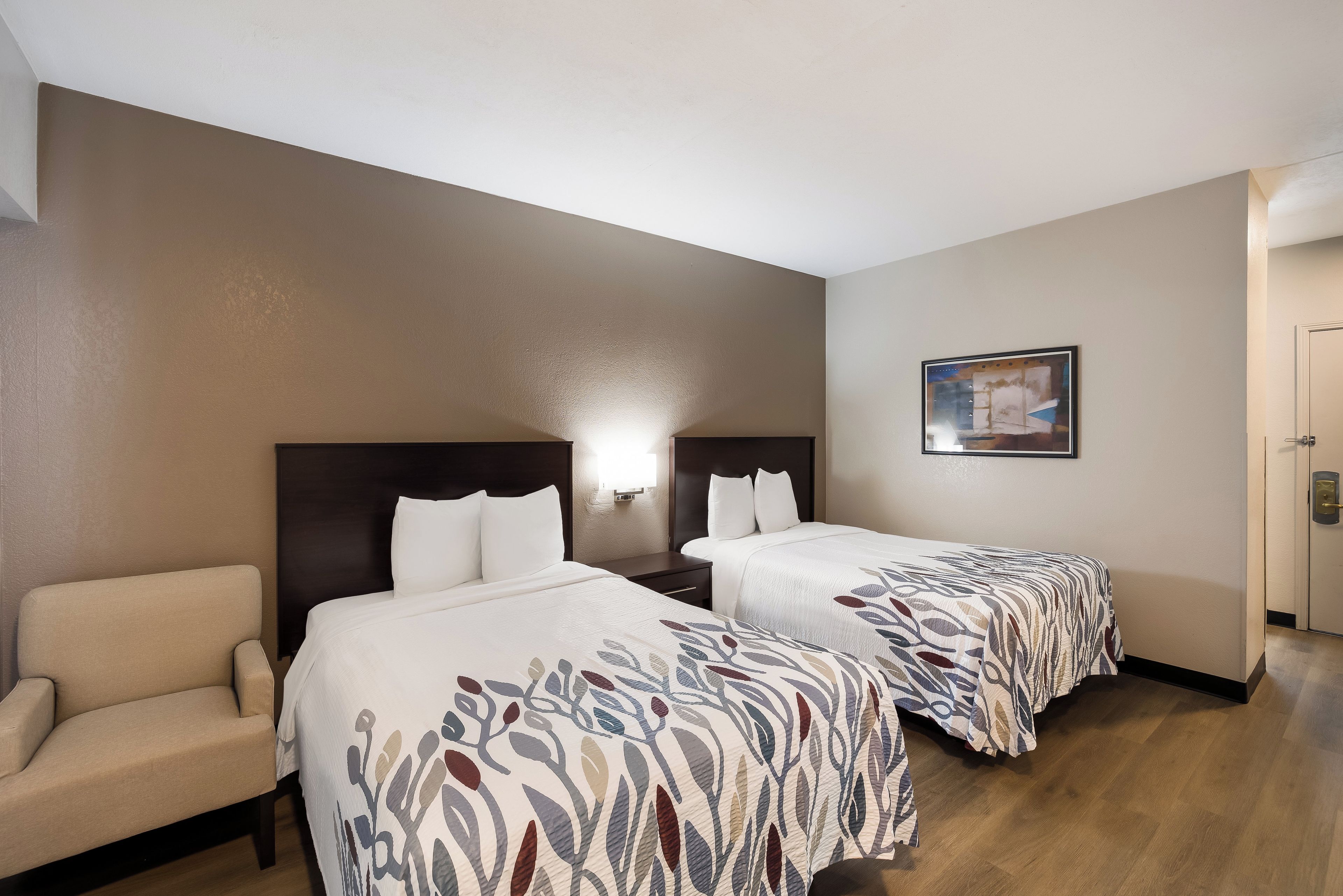 Ein Hotelzimmer mit zwei Betten, einem Sofa und einem Bild an der Wand.
