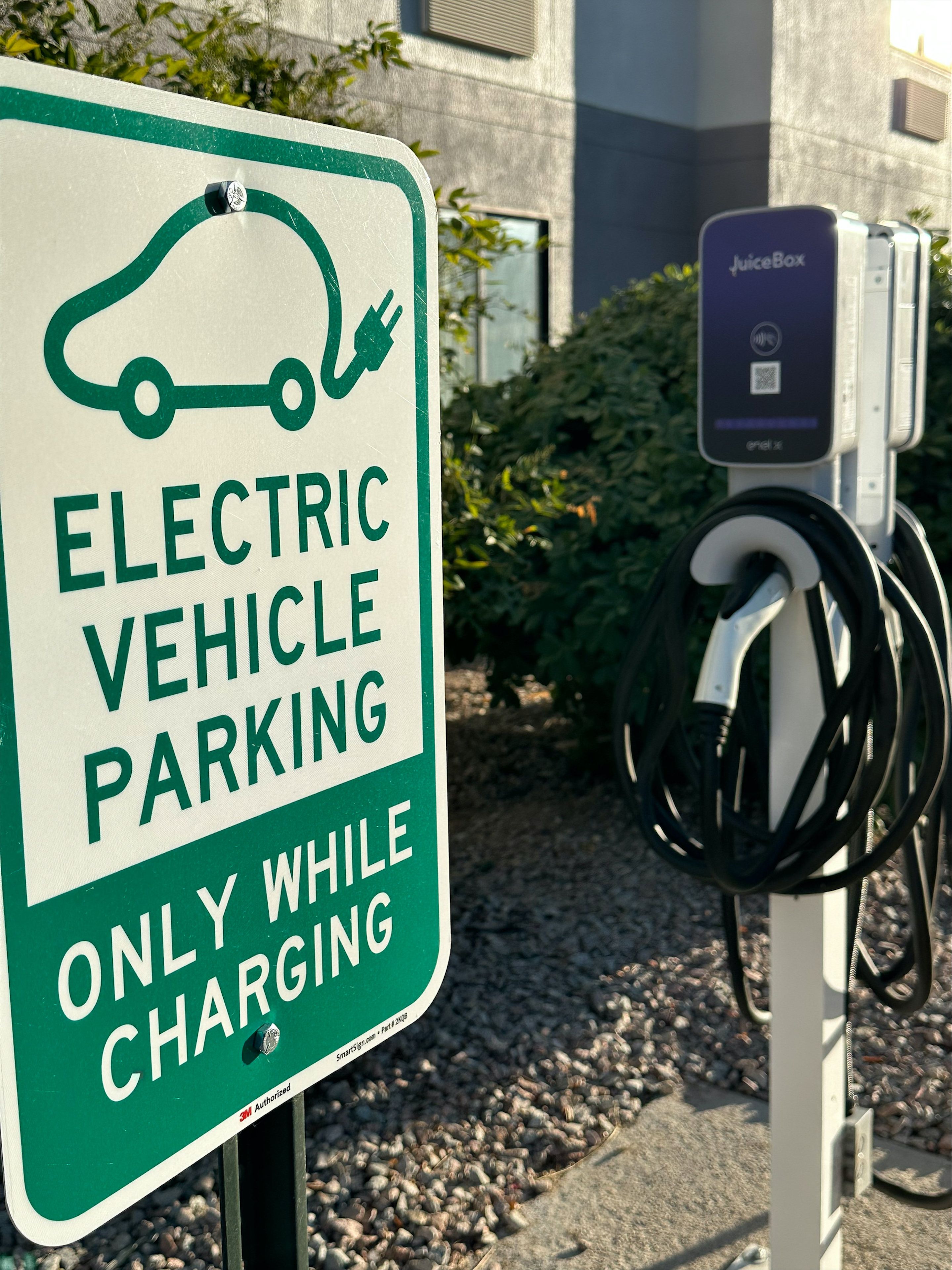 An electric vehicle charging station with a sign indicating it is for electric vehicle parking only while charging.