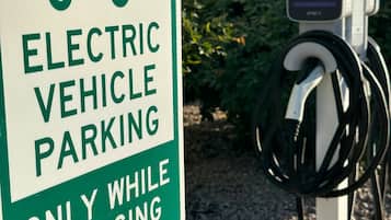An electric vehicle charging station with a sign indicating it is for electric vehicle parking only while charging.