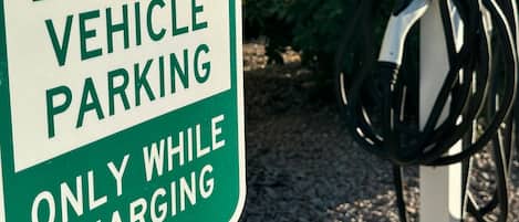 An electric vehicle charging station with a sign indicating it is for electric vehicle parking only while charging.