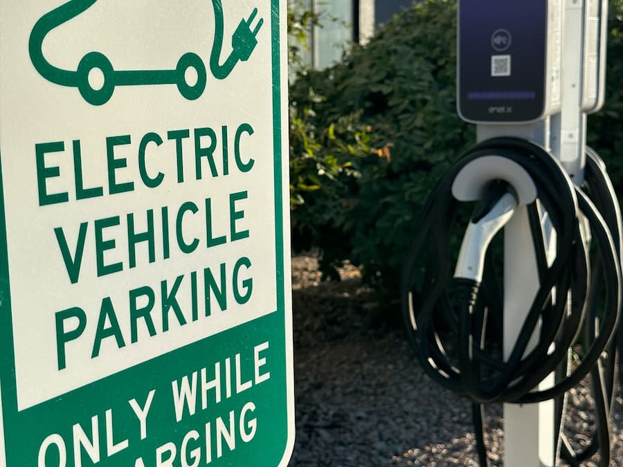 An electric vehicle charging station with a sign indicating it is for electric vehicle parking only while charging.