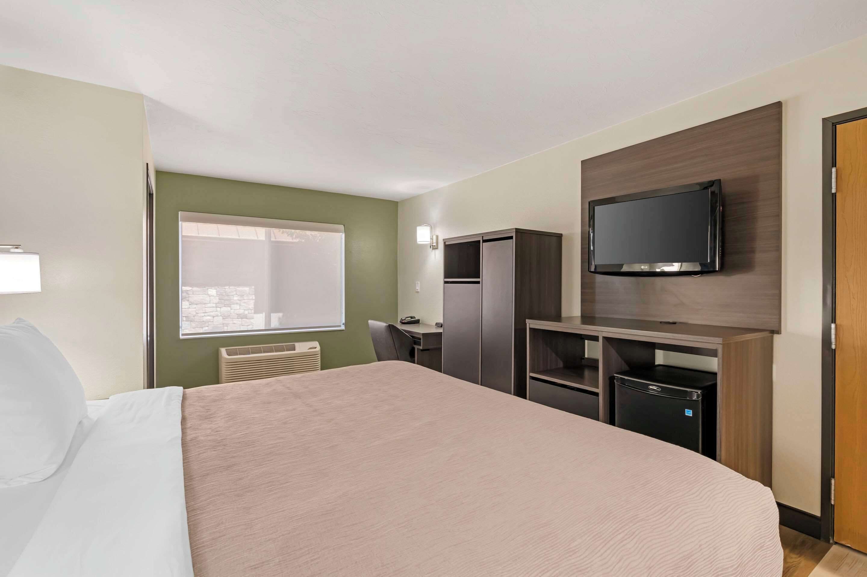 A hotel room with a bed, a desk, a television, and a wardrobe.
