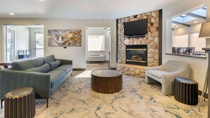 Una sala de estar moderna con un sofá gris, una mesa redonda de centro y una chimenea de piedra.
