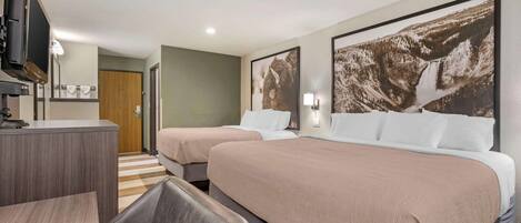 A hotel room with two beds, a desk, a chair, a TV, and a bathroom door.