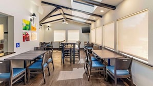 Un comedor moderno con techos altos, tragaluces y una larga mesa con sillas acolchadas de color azul.