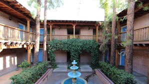 A courtyard with a central fountain, surrounded by brick buildings with wooden balconies and greenery. - Comfort Suites Tucson near Sabino Canyon (Tucson)