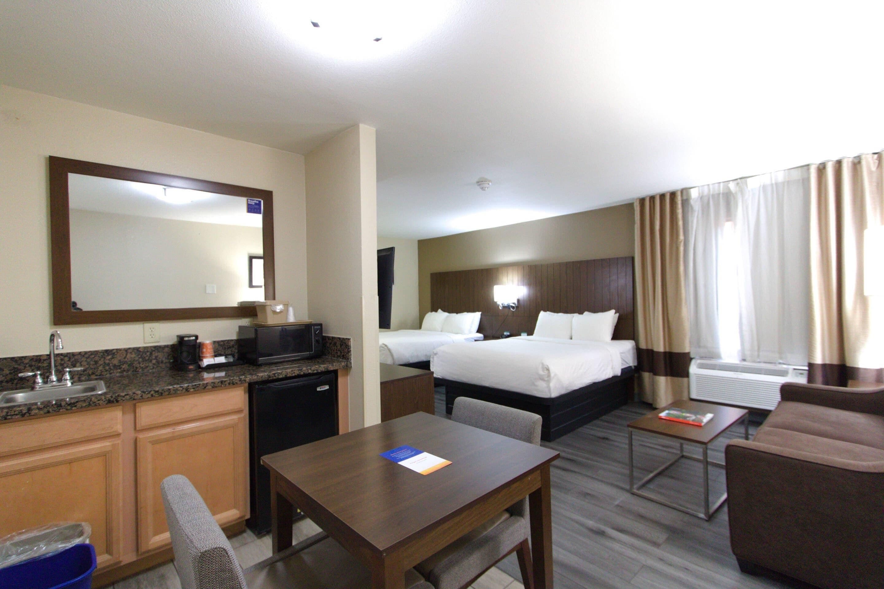 Habitación de hotel con kitchenette, cama, escritorio y zona de estar.