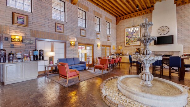 A spacious lobby with a fireplace, a fountain, a bar area, and a seating area with a blue sofa and red chairs. - Comfort Suites Tucson near Sabino Canyon (Tucson)