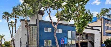 A modern hotel with a blue facade, a visible entrance, and a parking garage.