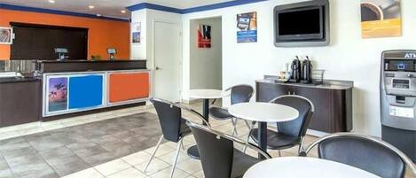Un moderno vestíbulo de hotel con mostrador de recepción, zona de estar y cajero automático.