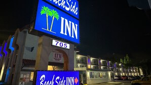 A building with a prominent 'BeachSide INN' sign, an 'ATM' sign, and a directional arrow sign. - Beachside Inn Motel (Anaheim)