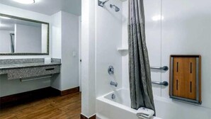 A bathroom with a shower, a vanity with a mirror, and a wooden cabinet. - Beachside Inn Motel (Anaheim)