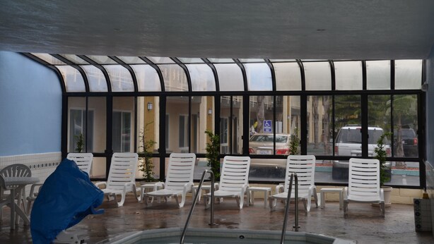 A covered outdoor seating area with white lounge chairs and a pool. - Beachside Inn Motel (Anaheim)