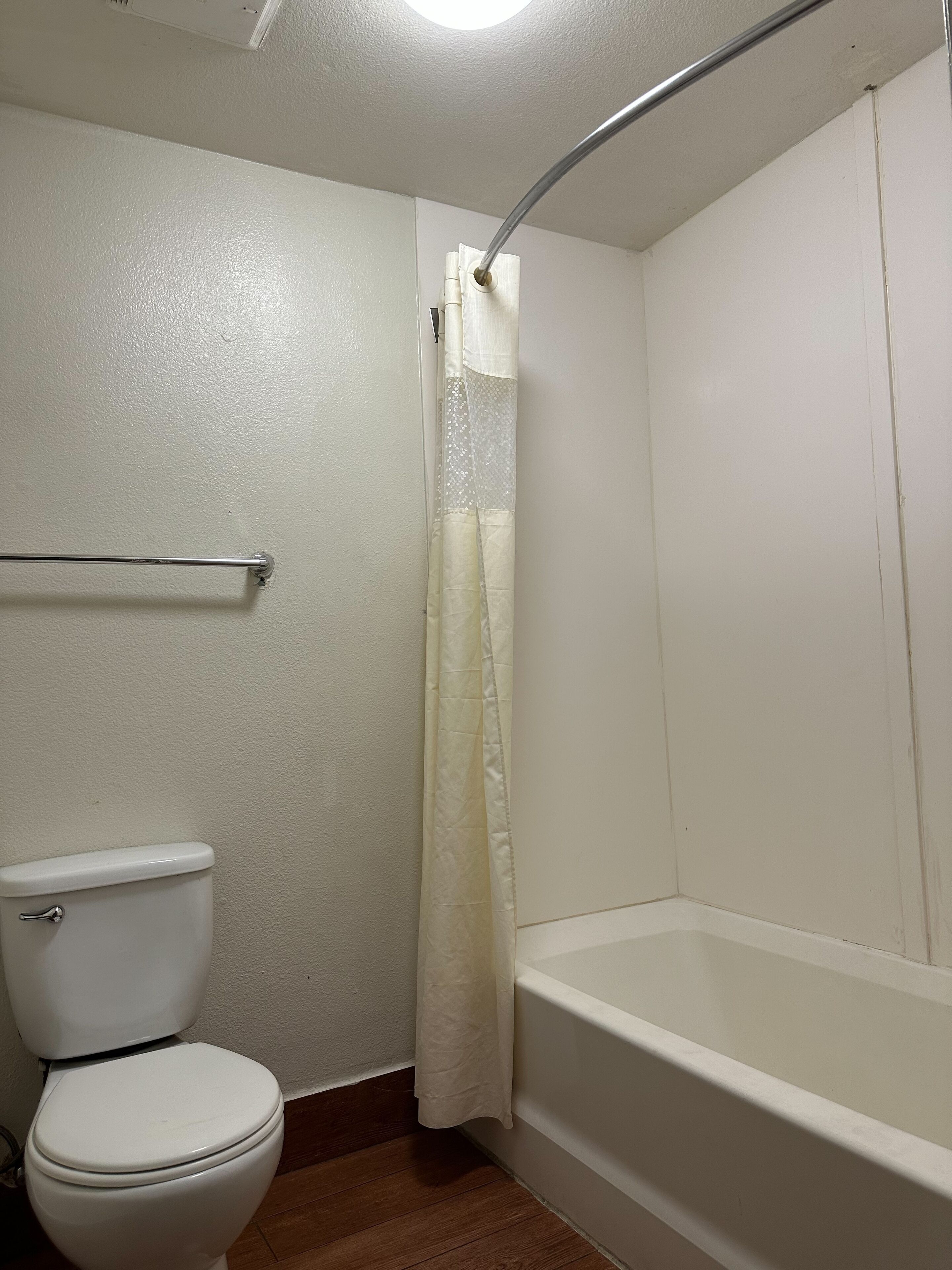 A bathroom with a toilet, a bathtub, and a shower curtain.