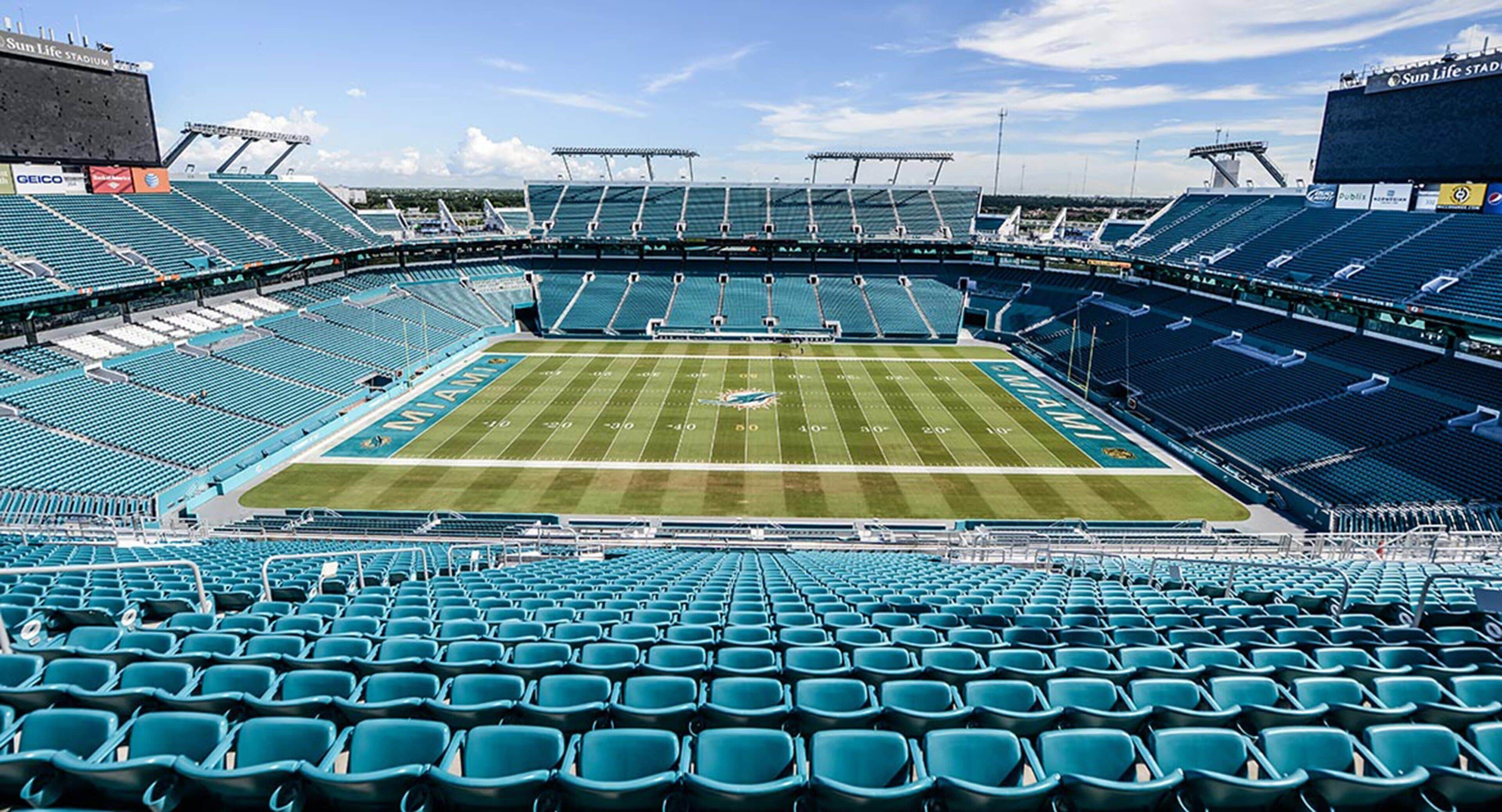 Un estadio con varios niveles de asientos, un campo de fútbol y un marcador grande.