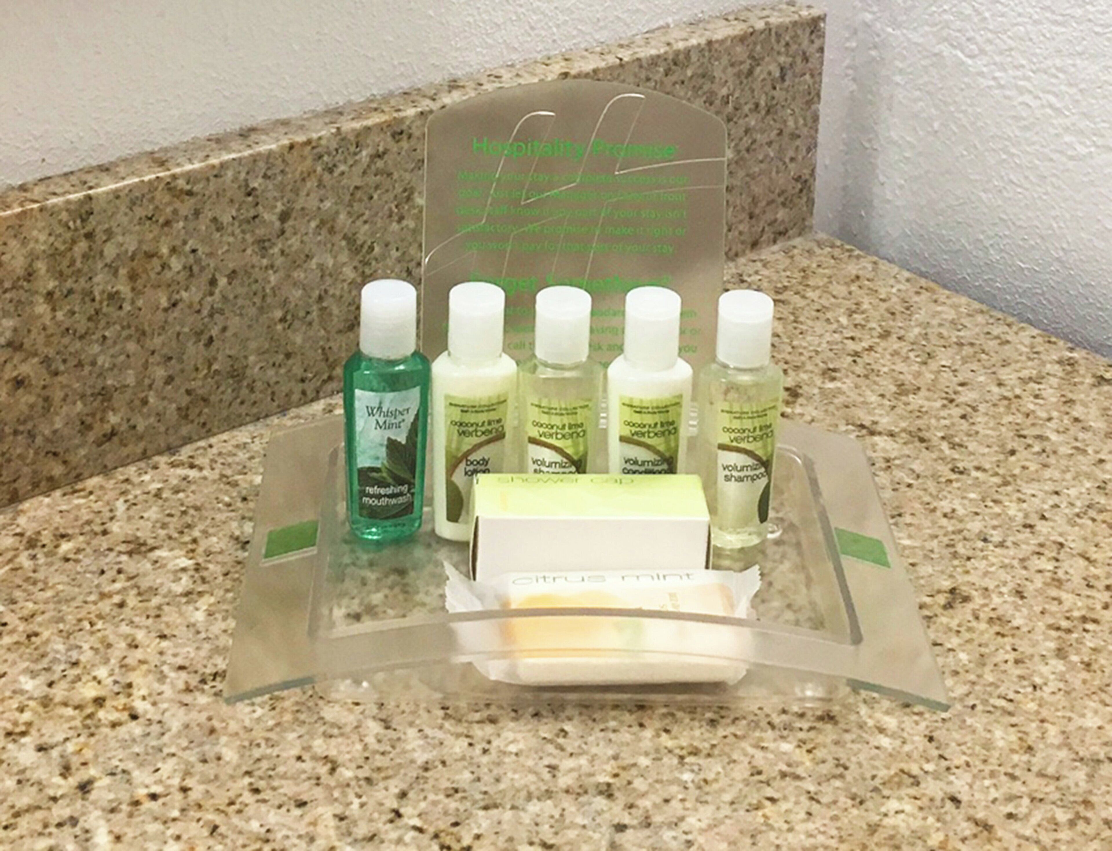 A hotel bathroom counter with a display of toiletries including mouthwash, body lotion, and shampoo.